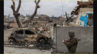جندي أوكراني يمر بجانب سيارة محترقة ، مع استمرار الهجوم الروسي على أوكرانيا ، في قرية كراسيليفكا خارج كييف