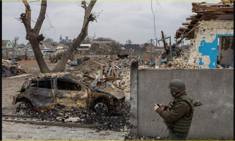 جندي أوكراني يمر بجانب سيارة محترقة ، مع استمرار الهجوم الروسي على أوكرانيا ، في قرية كراسيليفكا خارج كييف
